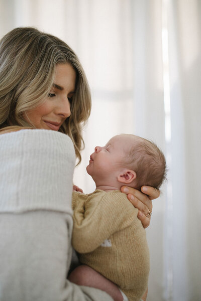 mother staring softly at her newborn baby as he smiles