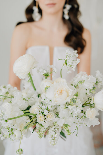 Photo of a white winter bouquet being held by a bride at The James House in Lincoln, Nebraska. Photo by Anna Brace, who specializes in wedding photography in NE.