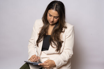 The professional dedicated to supporting female entrepreneurs. Dressed in a stylish white blazer and green pants, she's hard at work on her iPad, ready to assist you in achieving your business goals.