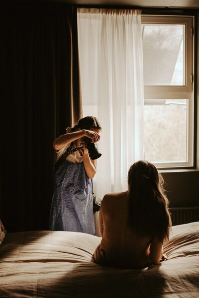 en gravid kvinna i kostym sitter på ett fält med ett stort leende
