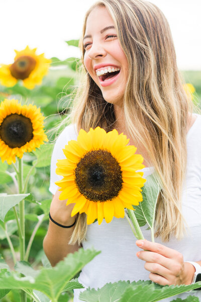Senior girl laughing holding sunflower