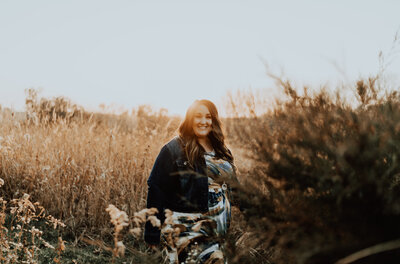 Nicole, owner of Haven Beauty Collective, standing in a golden field, embodying natural beauty, confidence, and holistic hair care values.