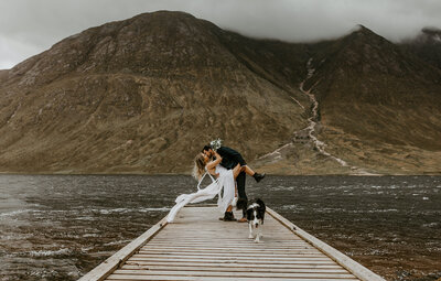 couple kissing in front of mountains on jetty