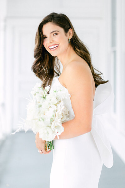 Bride in strapless wedding dress  laughing while holding flower bouquet