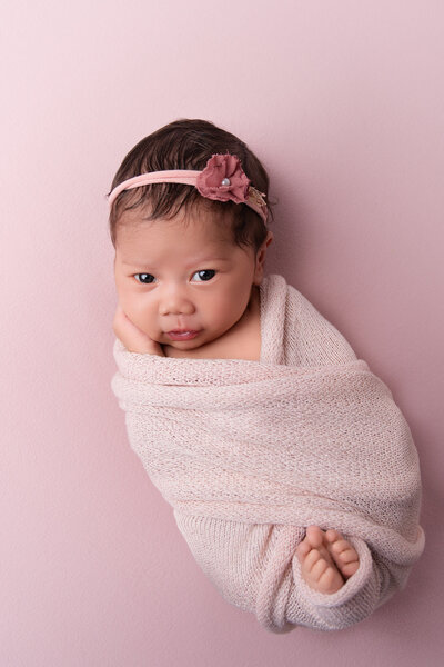 Newborn baby girl wrapped in pink and cute headband