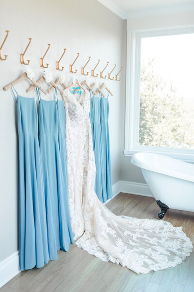 A wall of hangers with the wedding dress and bridesmaids' dresse sin the bridal suite.