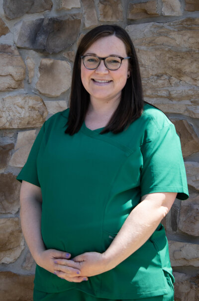 Danielle McCarty posing for a headshot behind a rustic stone wall. 