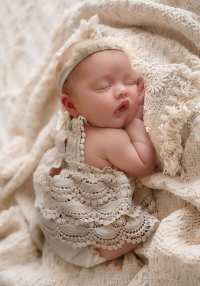 Baby girl milestone photo session in Fort Worth, sitting on a white chair with a bow headband and burgundy romper

