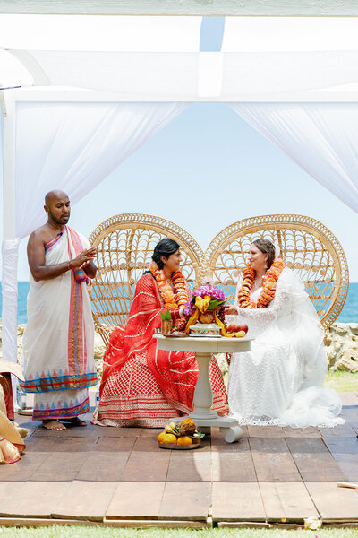 A wedding couple sitting in chairs during an Indian wedding ceremony. 