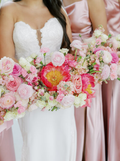 closeup of bridal bouquets with big pink peonies, ranunculus, and pink bridesmaid dresses