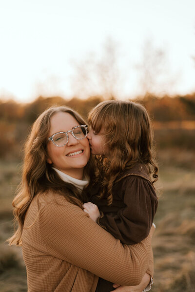 daughter gives mom a kiss for family photos in peoria il