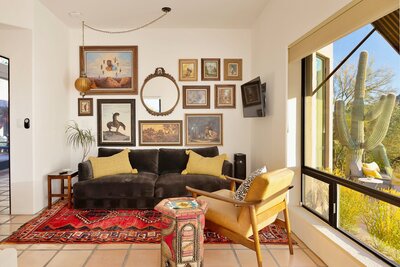 Sitting area off primary suite featuring a bright red vintage area rug and gallery wall of southwestern-style paintings.