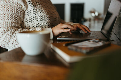 SEO strategist typing on her Macbook curating custom white label offers for her copywriter and website design clients.
