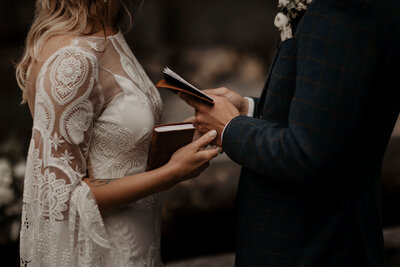 couple holding hands and vow books during private vows during romantic washington elopement