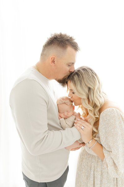 Dad kissing mom who is also kissing baby by Northern Virginia Newborn Photographer