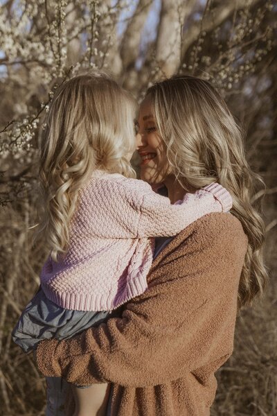 Mother holding toddler with warm sunlight and natural tones against Missouri spring scenery