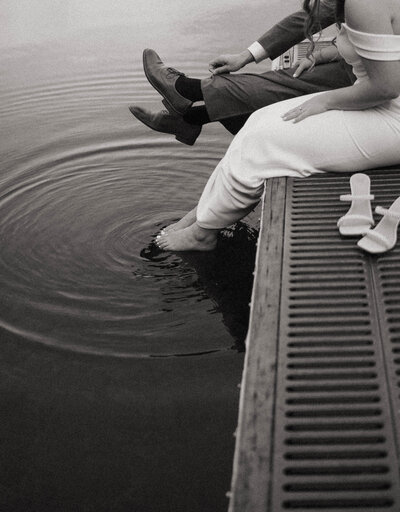 black and white image of couple dipping toes in water