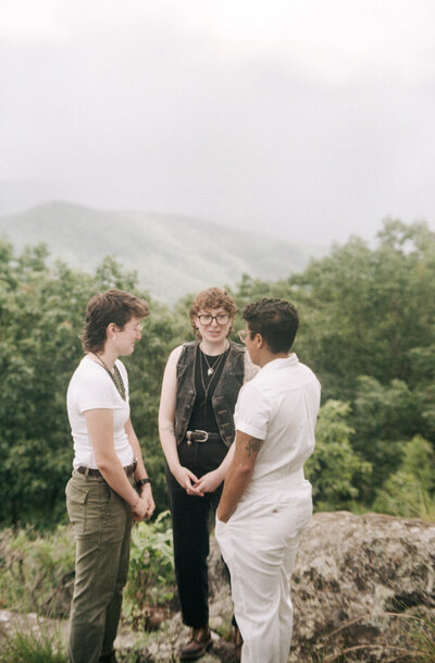 Cinematic wide shot of the couple embracing on the summit, with soft focus and natural light.
