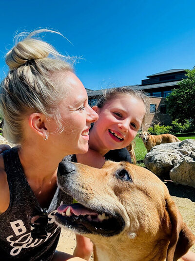 Caroline and her daughter sharing a moment of laughter, embodying harmony, healing, and heartfelt connection with their dog