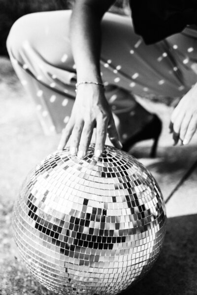 Woman's hand touching a disco ball with shining lights