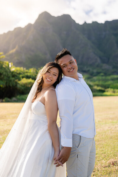 Oahu Hawaii Elopement bride and groom holding hands at Kualoa Regional Park montains sunrise.
