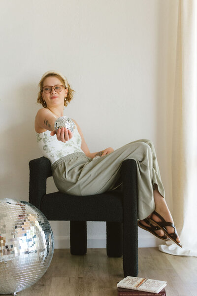 Confident branding image of Lillian, a wedding industry VA, pointing at the camera with a disco ball nearby.