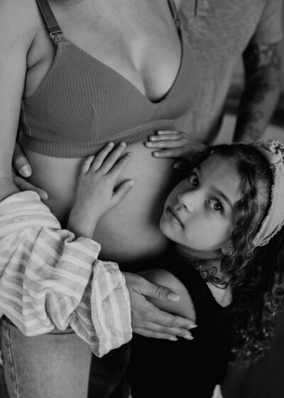 black and white portrait of daughter hugging her mom's pregnant belly