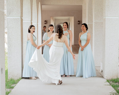 A catholic bride does a first look with her very surprised bridesmaids who are wearing light blue outside St. Anastasia Catholic church in St. Augustine, Florida.