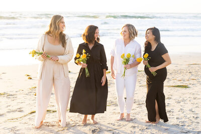Women holding flowers on the beach in La Jolla at sunset