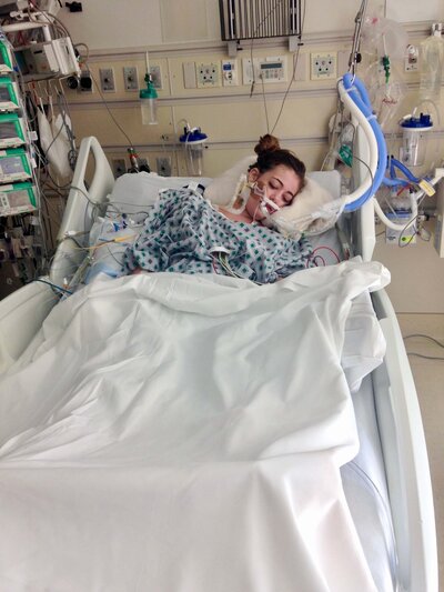 A photo of Madison in a coma in a hospital bed, symbolizing her strength and resilience after surviving septic shock and cardiac arrest.