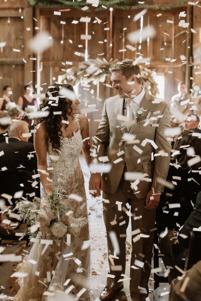 Wedding gown hanging on an ornate vintage clock in the bridal suite, photographed by Rainstorm Photo & Video to highlight elegant textures and timeless wedding details.