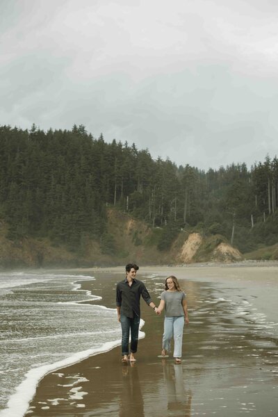 Engaged couple walking on the beach on the Oregon Coast. Tillamook, OR Engagement Photos