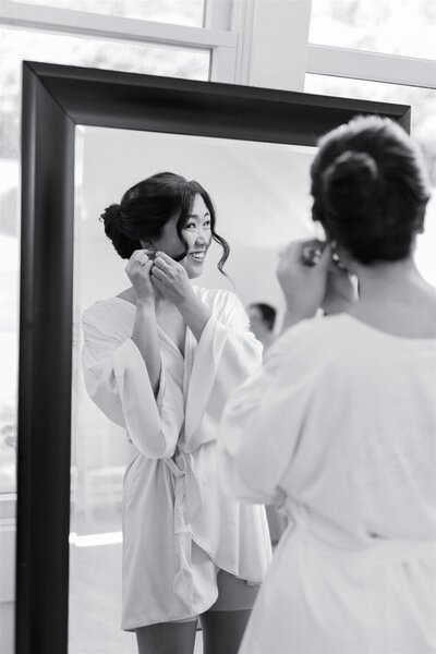 A person looking in a mirror and putting in earrings 