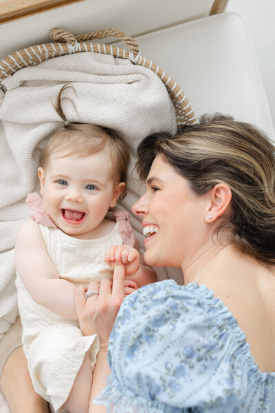 Mother laughs with her giggling baby at photography session