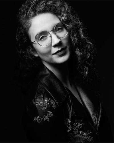 Black and white headshot of the owner of a communication and public speaking consulting company, smiling confidently at the camera.