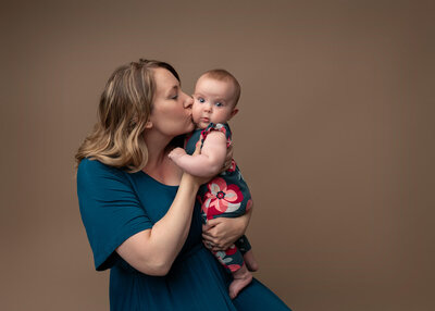 motherhood portrait of mom holding and kissing her baby