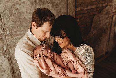Embracing their new baby girl, a couple soaks in these fleeting moments during a studio newborn session at Nikii Pix Photography Studio in Bismarck. 