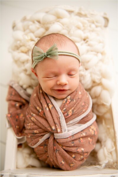 newborn smiling wrapped in floral blanket