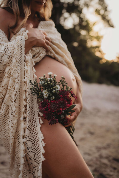 mother holding exposed baby bump with flowers - the woodlands texas maternity photography