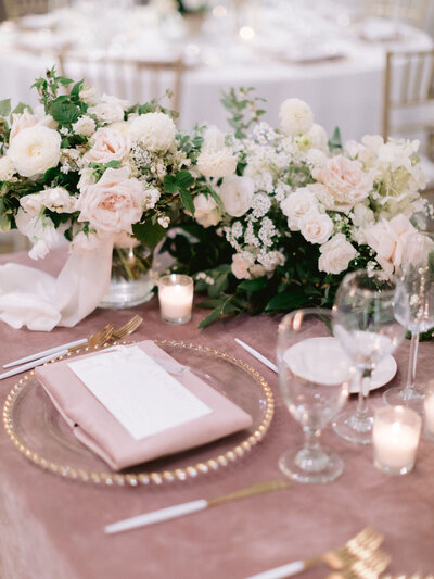 pink table cloth covering a table with white and pink flowers and crystal dishes