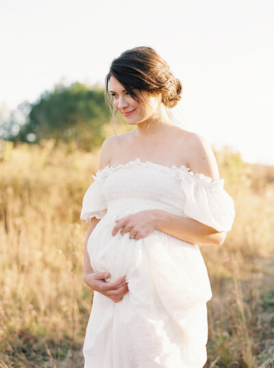 Pregnant woman holding her belly in a field