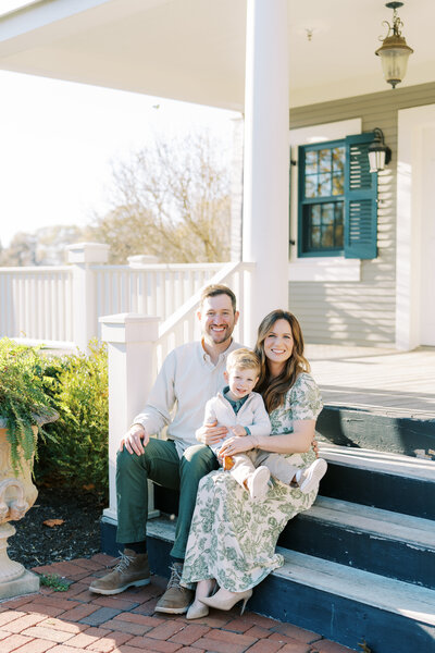 a family sitting on the porch steps of their home