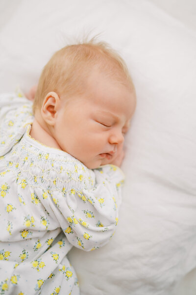 Newborn baby girl sleeps on white pillow during in-home newborn session