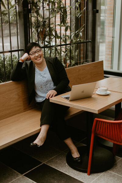 Person sitting at a café table with a laptop and coffee.