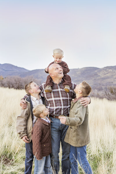 toddler holding and hugging four sons in a mountain field