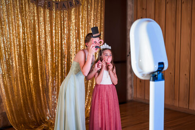 Kids using the Dallas Fort Worth Photo Booth at a wedding, they have props on their faces..