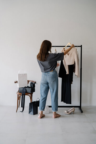 Woman reviewing clothes on a rack during a personal styling session 