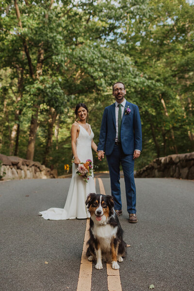Couple poses behind dog on road