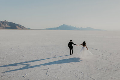 couple running through sand dunes