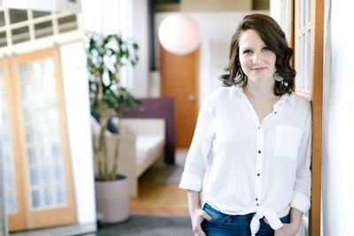 systems and strategy owner caitlyn gray looking at camera while leaning against the wall getting ready for setting up honeybook for her next client